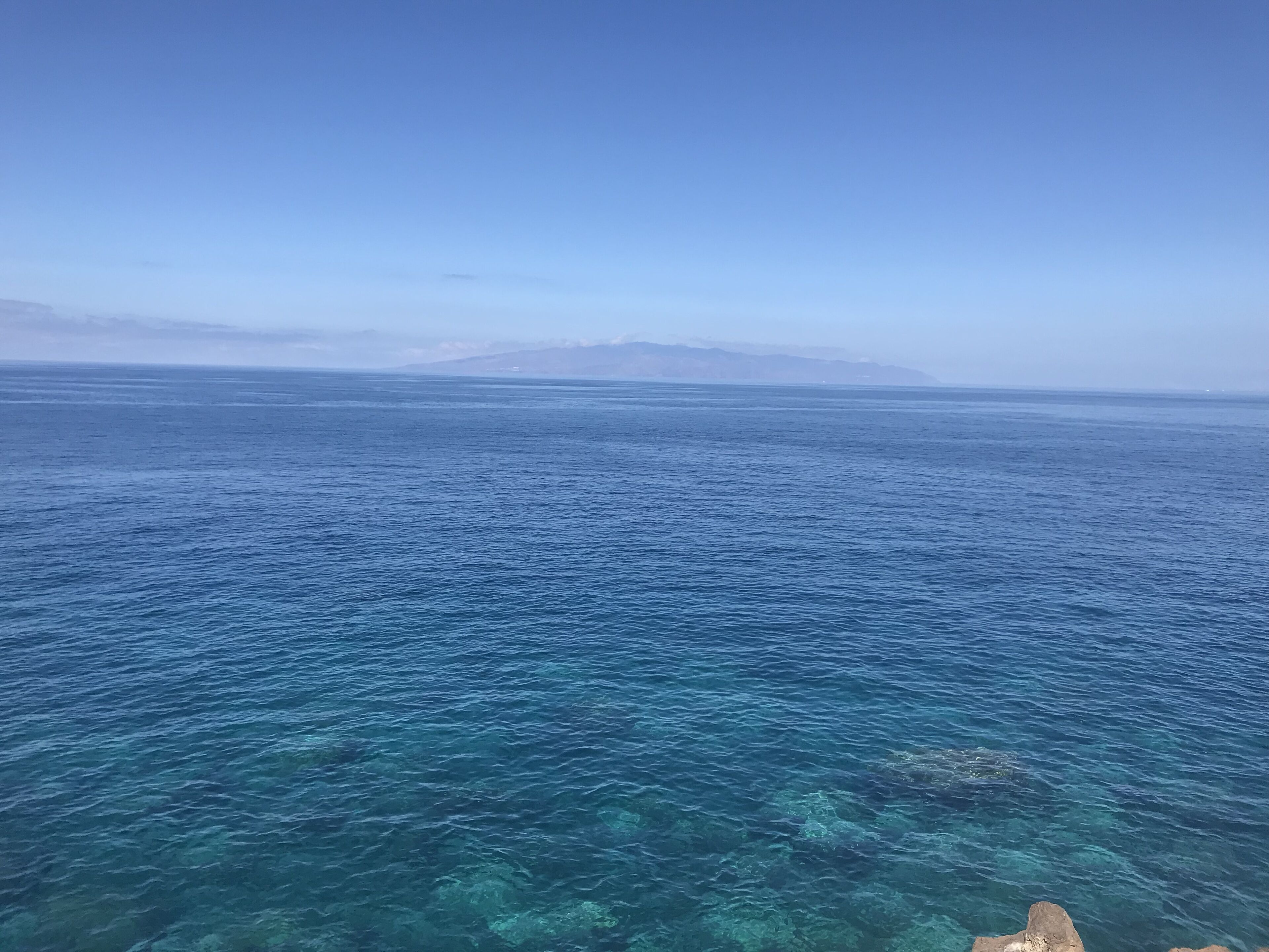 A clear view of a coastal area with calm sea waters and distant landforms.