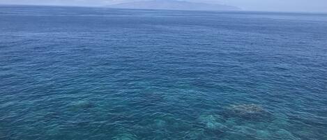 A clear view of a coastal area with calm sea waters and distant landforms.