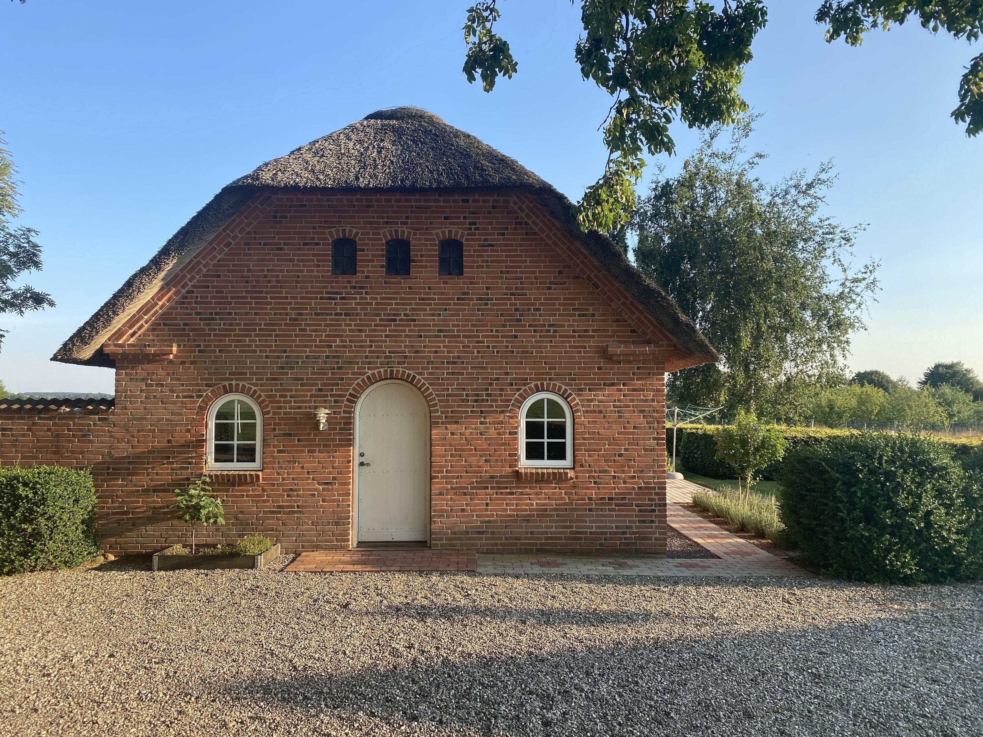 Un bâtiment en briques doté d’un toit à deux versants et de trois fenêtres en arc.
