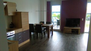 A compact kitchen with modern appliances, a dining area with a table and chairs, and a television in a living area. - Comfortable child-friendly holiday apartment, Baltic Sea, Usedom, beach, fishing (Peenemünde)