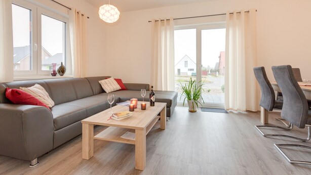 A modern living room with a grey sofa, wooden coffee table, and a dining area with two chairs. - Holiday home on the Baltic Sea - up to 6 persons (4 stars) (Zierow)