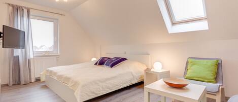 A modern bedroom with a bed, bedside table, and a small table with a bowl.