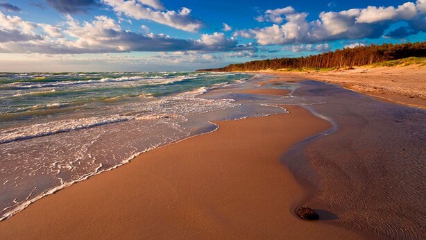 Ein Strand mit sandigem Ufer und Wellen.