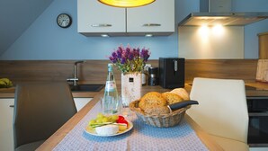 Eine moderne Küche mit einem Esstisch für zwei Personen, komplett mit einer Wasserflasche, einer Weintraubenteller, einem Brotkorb und einem Blumenstrauß.