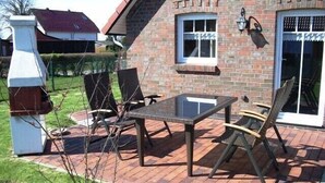 Un patio con pavimento in mattoni, un tavolo in vetro e due sedie.