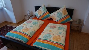Ein Bett mit zwei Kissen und einer Decke, ein Nachttisch und eine kleine Lampe.