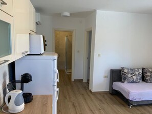 A compact living space with a kitchenette, a shower, and a sofa with patterned cushions. - Apartment in Punat with Terrace, Air condition, WIFI, Washing machine (4534-3) (Punat)