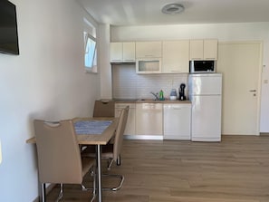 A modern kitchen with white cabinets, a microwave, a refrigerator, and a dining area with a table and chairs. - Apartment in Punat with Terrace, Air condition, WIFI, Washing machine (4534-3) (Punat)
