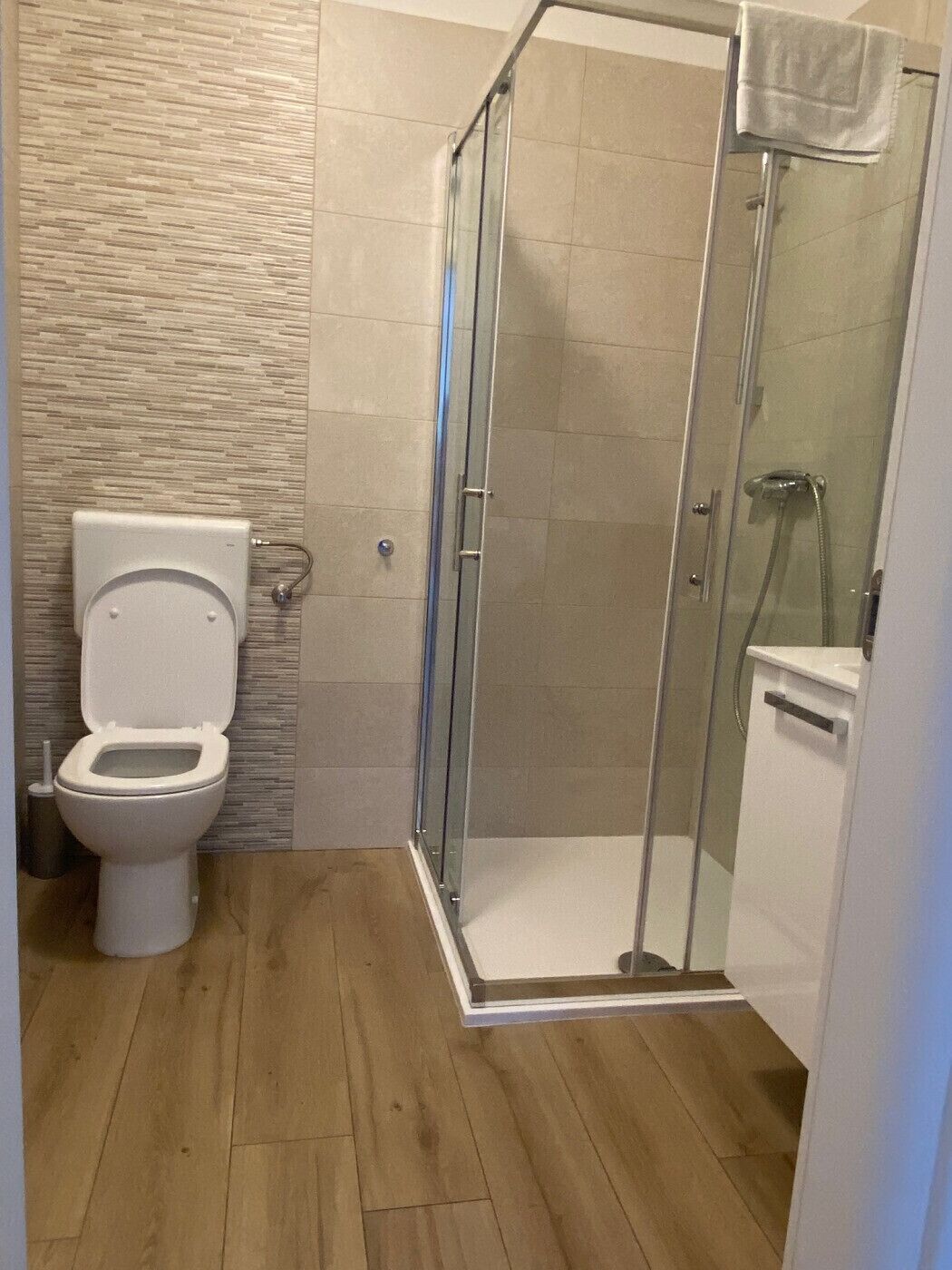 A bathroom with a toilet, a shower with a glass door, and a tiled floor.
