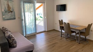 Une pièce comprenant une table à manger, des chaises, un canapé, un téléviseur et une fenêtre donnant sur un beau paysage.