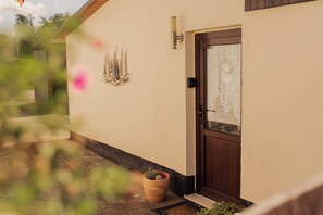 Una casa con puerta de madera, planta en maceta y aplique de pared.
