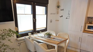 A cozy kitchen with a dining table, chairs, a potted plant, and a wall with coffee-related decorations. - Vacation apartment Marie in Bergen auf Rügen, quiet location (Bergen auf Rügen)