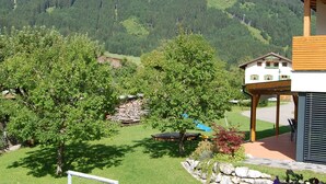 Una propiedad residencial con césped cuidado, una terraza de madera y vistas a un paisaje montañoso.