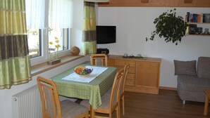 Una sala de estar acogedora con comedor, muebles de madera, un televisor y una estantería.