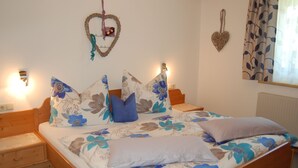 Una cama bien hecha con ropa de cama floral, una mesita de noche y luces empotradas en la pared.