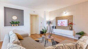 A modern living room with a sofa, a coffee table, and a TV mounted on the wall.