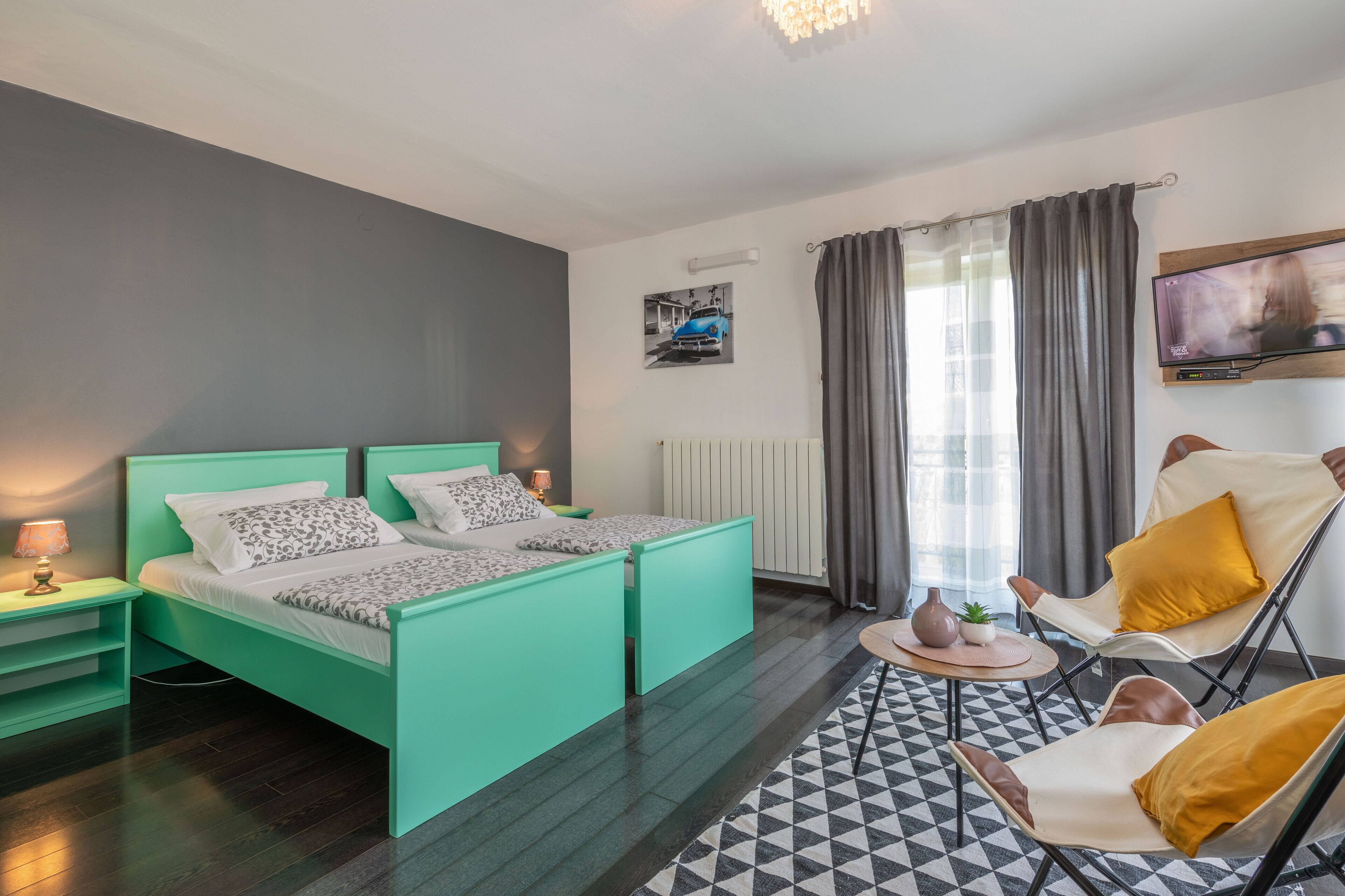 Una camera da letto moderna con un letto verde acqua, una TV a parete e un tappeto decorato.