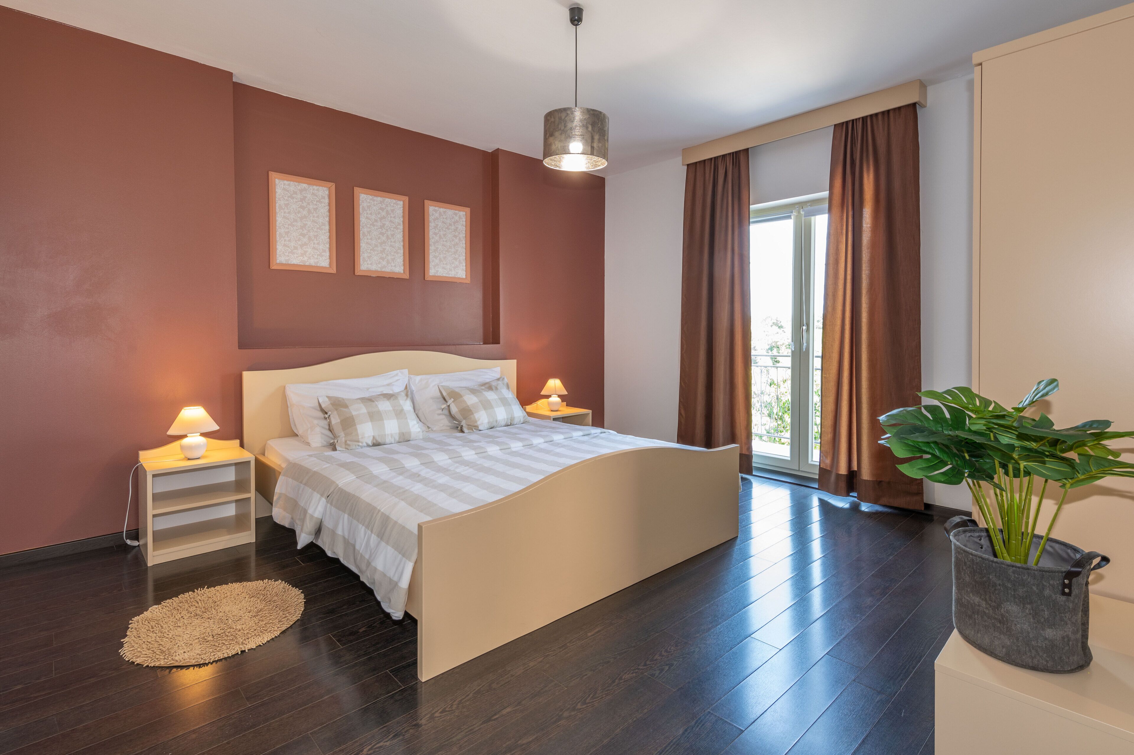Una camera da letto moderna con un letto grande, lampade da comodino, una pianta in vaso e vista sull'esterno.