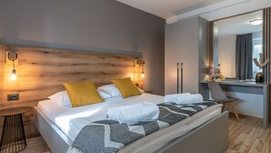 A modern bedroom with a large bed, a desk, and a mirror.