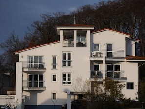 A multi-story building with balconies, large windows, and a flat roof. - Central location, south-facing balcony, own ground-floor bicycle storage room, e-car charging station. (Binz)