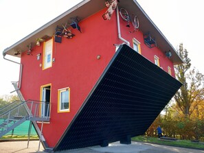 A red building with a large black awning, a staircase, and a bicycle rack on the roof.