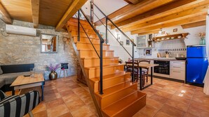 Eine rustikale Küche mit einer Holztreppe, Steinwänden und einem blauen Kühlschrank.
