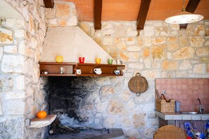 A stone fireplace with a shelf above it holding various kitchen items.
