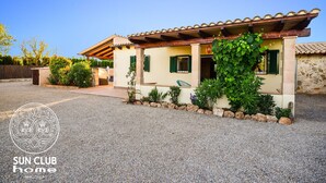 Een huis in mediterrane stijl met een pannendak, stenen muren en een grindpad.