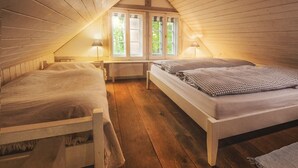 A cozy attic bedroom with two beds, wooden walls, and a window with natural light. - historical house in Heidevillage on the outskirts of forest (Natendorf)