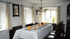 A dining room with a long table set for a meal, featuring white tablecloths, blue and white patterned plates, and yellow napkins. - Living in the listed house like grandma without having to compromise on comfort (Schernfeld)
