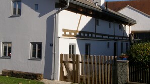 A two-story building with a white facade, a wooden fence, and a chimney. - Living in the listed house like grandma without having to compromise on comfort (Schernfeld)