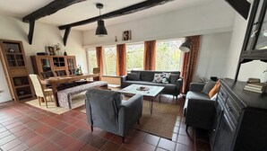 A living room with a fireplace, a dining area, and a large window with curtains. - Great facilities! Close to town! Calm! (Oldenburg)