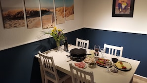 Spisebord med hvide stole, en vase med blomster og forskellige retter, herunder kød og grøntsager.