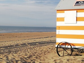A beachside building with a striped exterior, a wheelbarrow, and a view of the ocean. - Holiday Duinenwind - holiday in Belgium (De Haan)