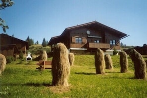 A rustic wooden building with a sloped roof, surrounded by hay bales and a grassy field. - Wooden chalet at 1,800 m above sea level at the edge of Nockberge National Park (Patergassen)
