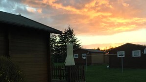 A residential area with a wooden building, a fenced yard, and a clear sky with clouds.