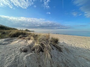 A sandy beach with dunes and a clear sky.