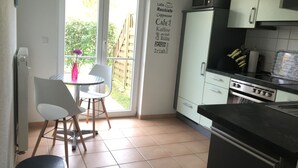 A kitchen with a dining area, a microwave, a refrigerator, and a wall with coffee-related words.