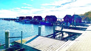 A waterfront dock with several wooden buildings, likely accommodations, connected by a pier.