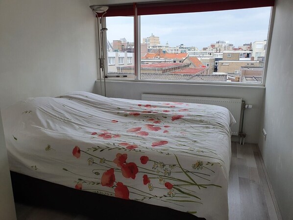 A bedroom with a bed, a window, and a radiator.