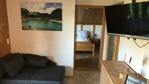 A cozy room with a bed, a sofa, a TV, and a welcome sign. - Charming vacation rental in a secluded location with a wonderful view (Bayerniederhofen)