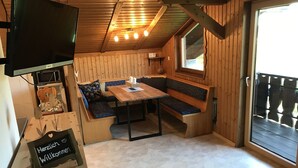 A cozy cabin interior with a wooden bench seating area, a table, and a television mounted on the wall. - Charming vacation rental in a secluded location with a wonderful view (Bayerniederhofen)