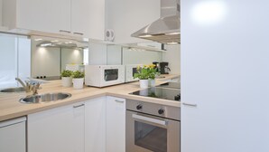 Een moderne keuken met roestvrijstalen apparatuur, witte keukenkastjes en een kleine plant in een pot op het aanrecht.