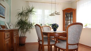 Un coin repas comprenant une table en bois, quatre chaises, une plante en pot et un meuble.