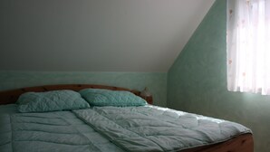 Une chambre à coucher avec un lit, des oreillers, une table de chevet et une fenêtre avec des rideaux.