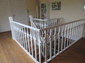 A room with a white wooden staircase, a bookshelf, and a door. - Apartment Ummanz - Pension Waldrose (Sellin)