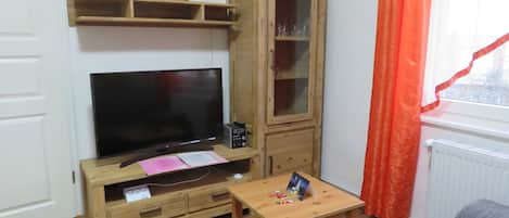 A living room with a TV, wooden cabinet, and a small table.