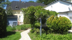 Ein Wohngebiet mit einem gepflasterten Weg, einem weißen Haus, einer Garage und einem Baum.