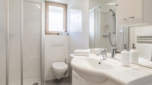 Un baño moderno con ducha, inodoro, lavabo y espejo.