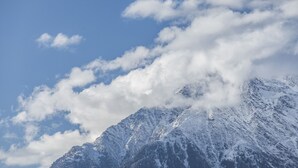 Una montaña nevada con cielo despejado y nubes.
